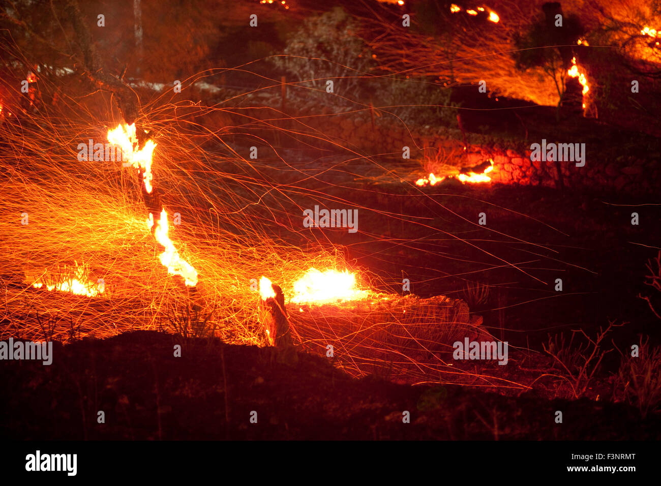 Streifen von Funkenflug Feuer und brennenden Baum Zweige Afterglow in einer verheerenden Nachtansicht Platy Dorf brennenden Website. Stockfoto
