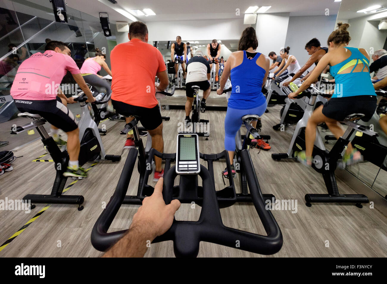 Ego-Perspektive eines Mannes Reiten ein stationäres Fahrrad bei einem Spinning-Kurs in der Turnhalle Stockfoto