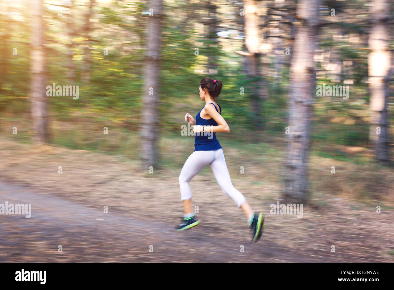 Junge Frau auf einer Landstraße bei Sonnenuntergang im herbstlichen Wald ausgeführt. Lifestyle-Sport-Hintergrund Stockfoto