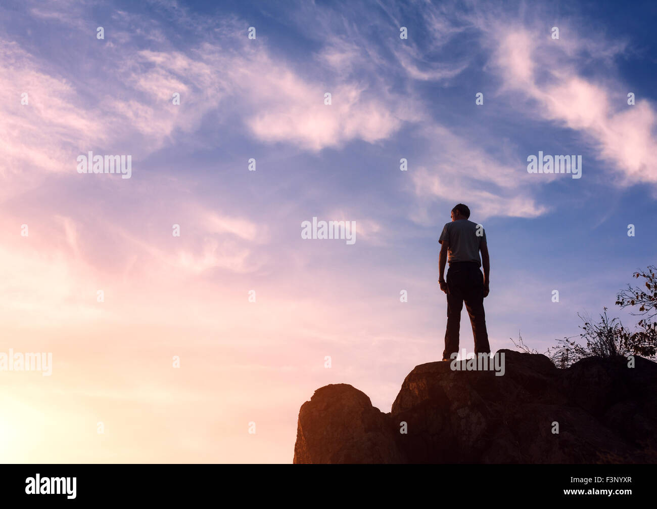 Silhouette eines Mannes mit angehoben bis Armen an den wunderschönen Sonnenuntergang auf dem Berg. Hintergrund Stockfoto