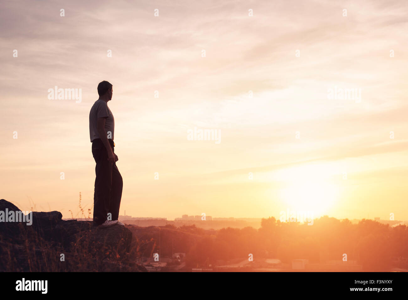 Silhouette eines Mannes mit angehoben bis Armen an den wunderschönen Sonnenuntergang auf dem Berg. Hintergrund Stockfoto