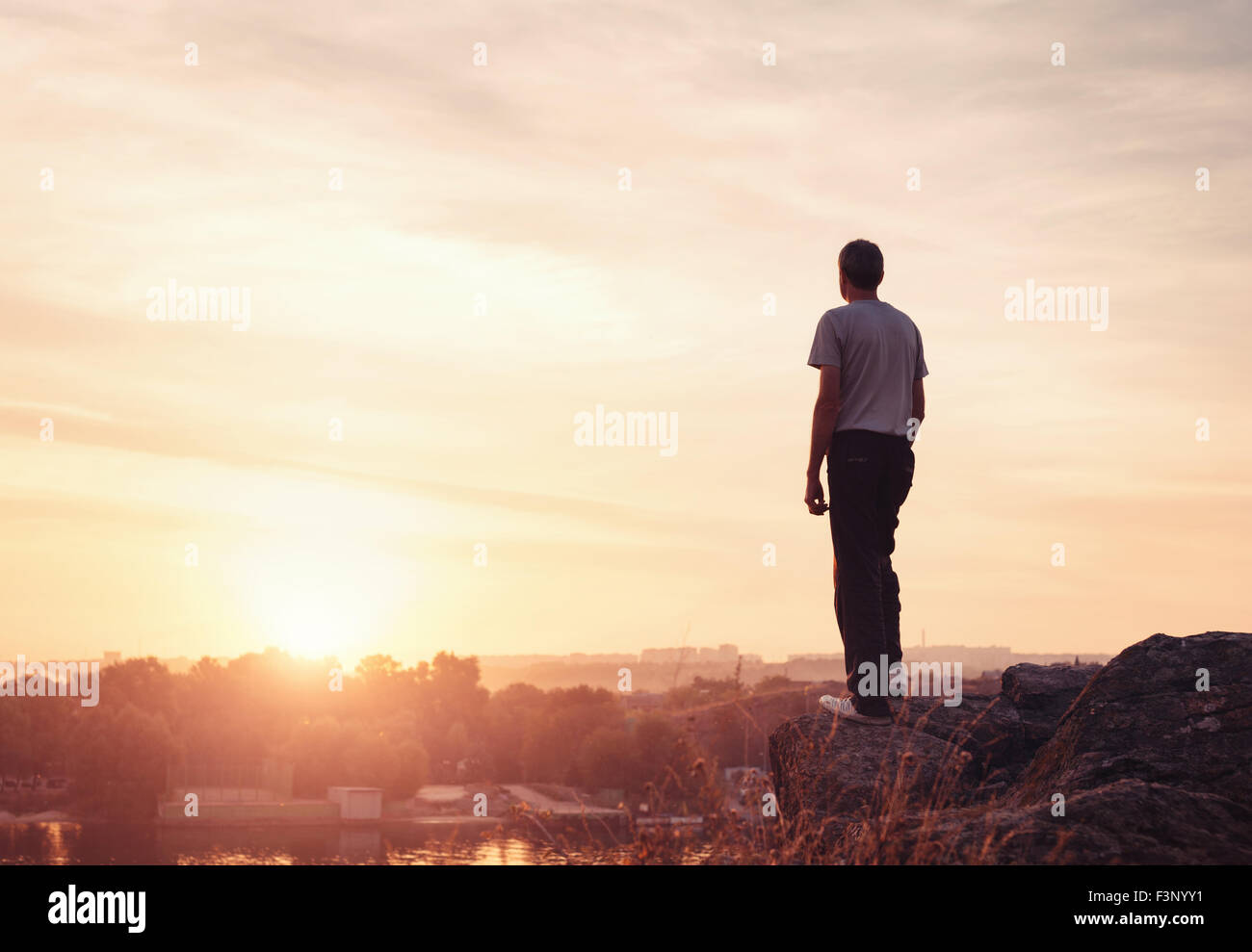 Silhouette eines Mannes mit angehoben bis Armen an den wunderschönen Sonnenuntergang auf dem Berg. Hintergrund Stockfoto