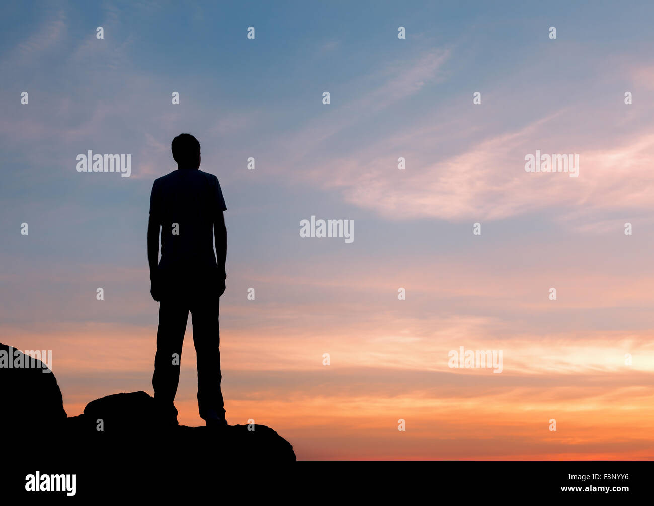 Silhouette eines Mannes mit angehoben bis Armen an den wunderschönen Sonnenuntergang auf dem Berg. Hintergrund Stockfoto