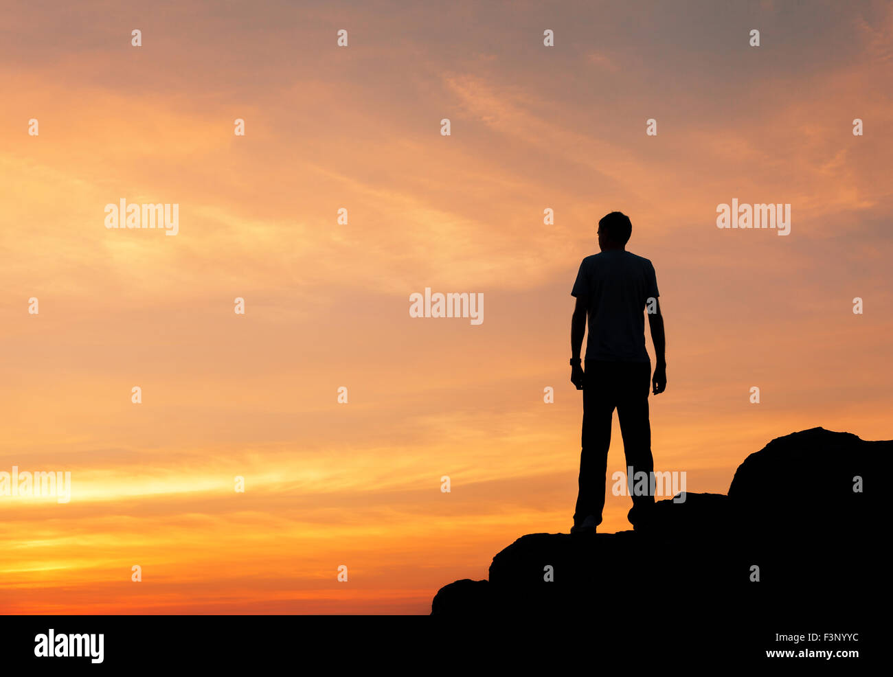 Silhouette eines Mannes mit angehoben bis Armen an den wunderschönen Sonnenuntergang auf dem Berg. Hintergrund Stockfoto