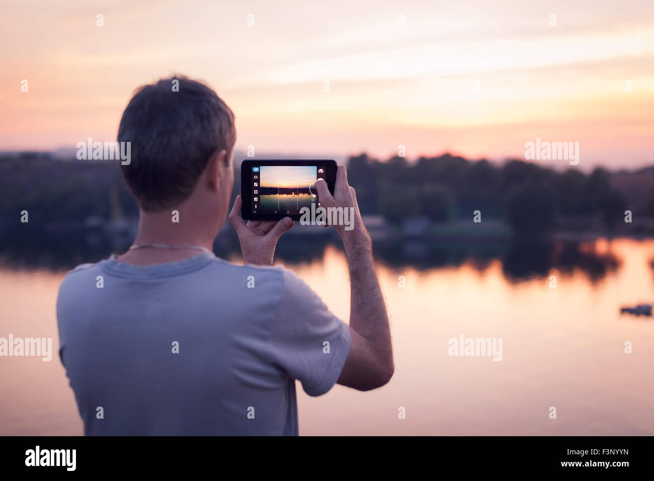 Mann mit Tab macht Foto des Sonnenuntergangs. Hintergrund Stockfoto