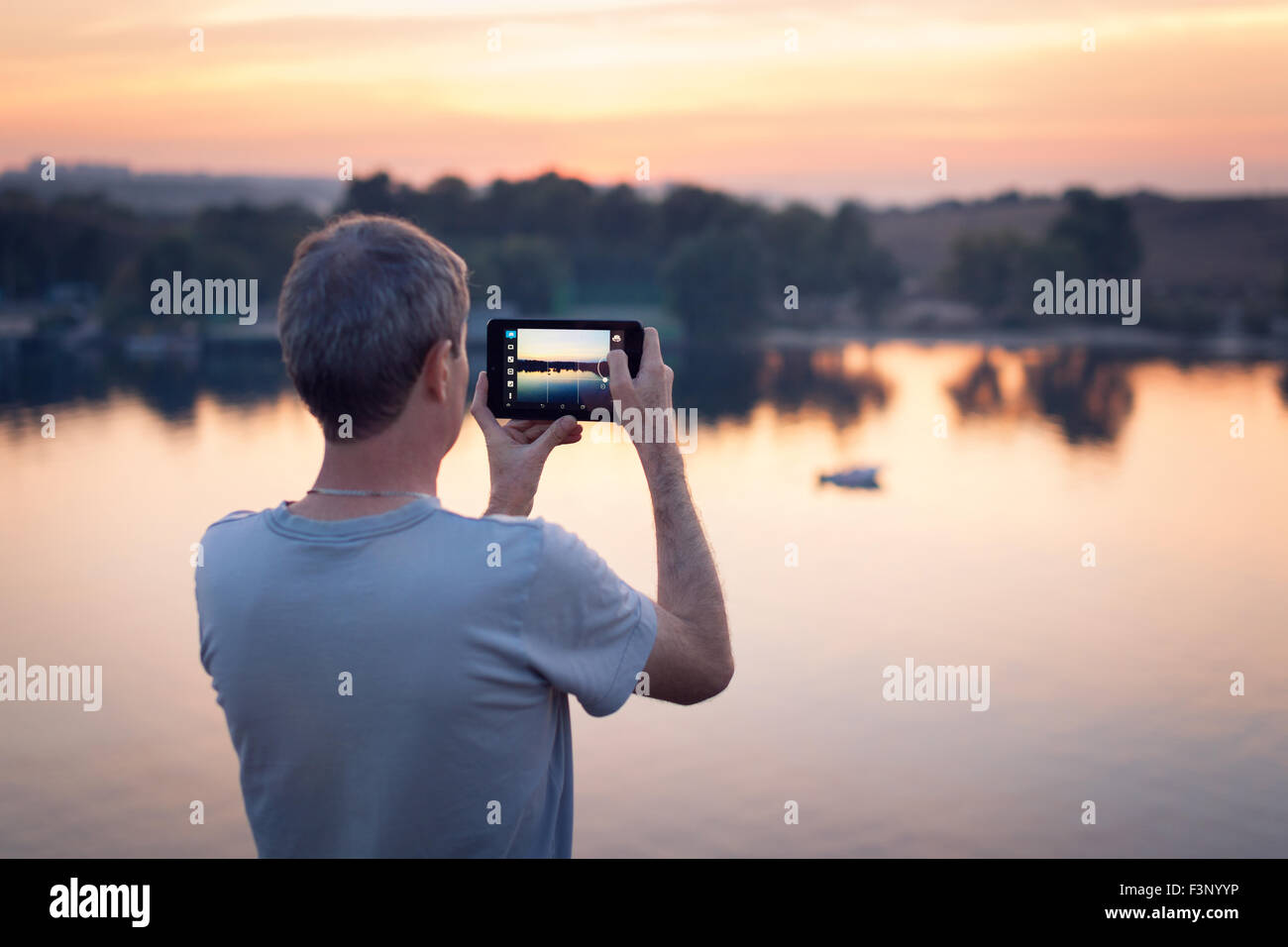 Mann mit Tab macht Foto des Sonnenuntergangs. Hintergrund Stockfoto