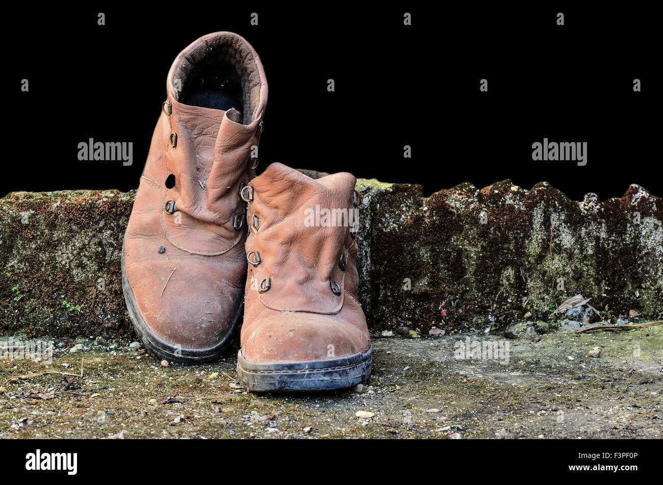 Schmutzige alte Schuhe auf schwarzem Hintergrund Stockfoto