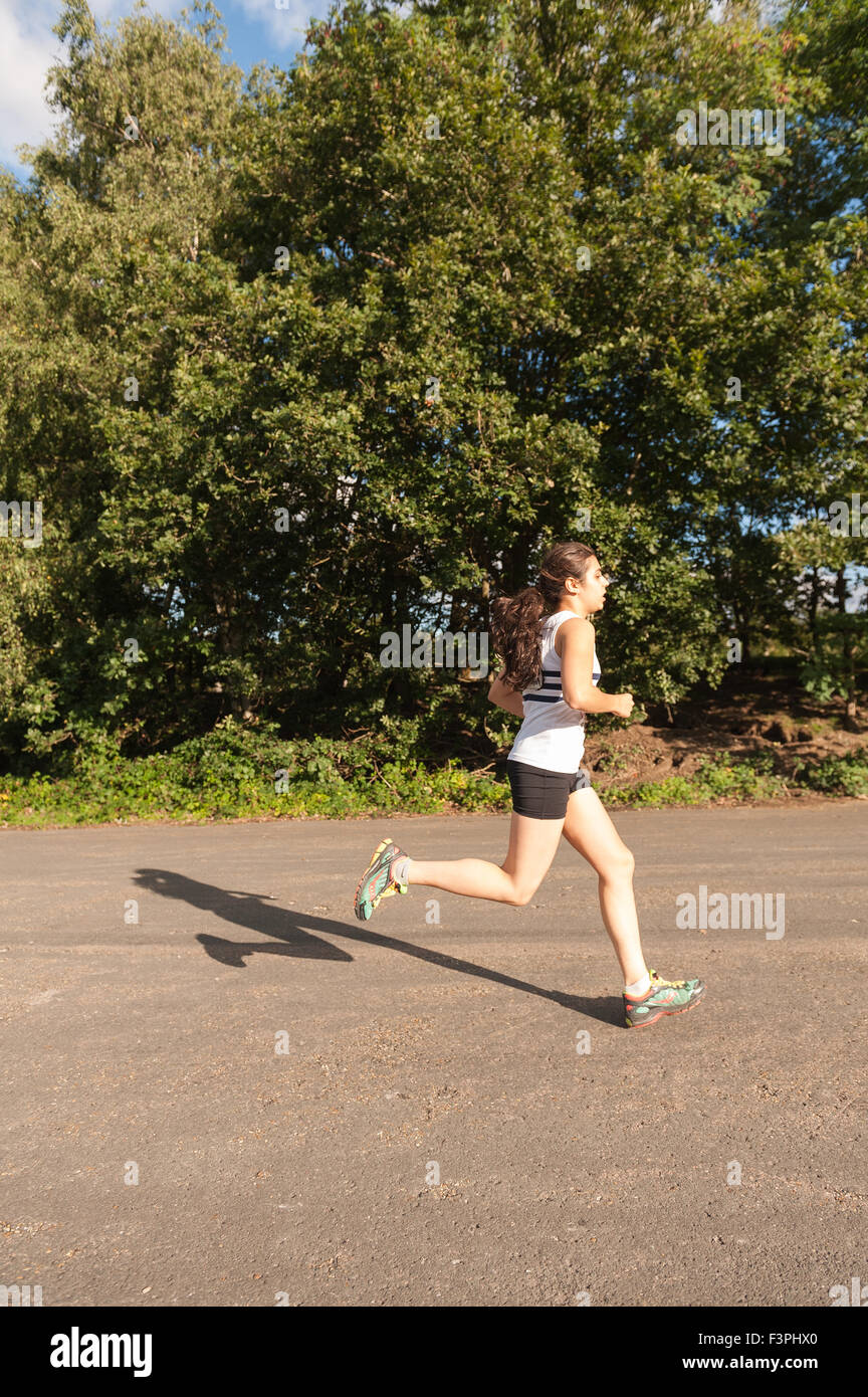 Junge Dame sprinten und laufen bis zur Ziellinie in einem Langlauf-Straße-Staffellauf mit Schaulustigen hinter Metall Barrieren Stockfoto