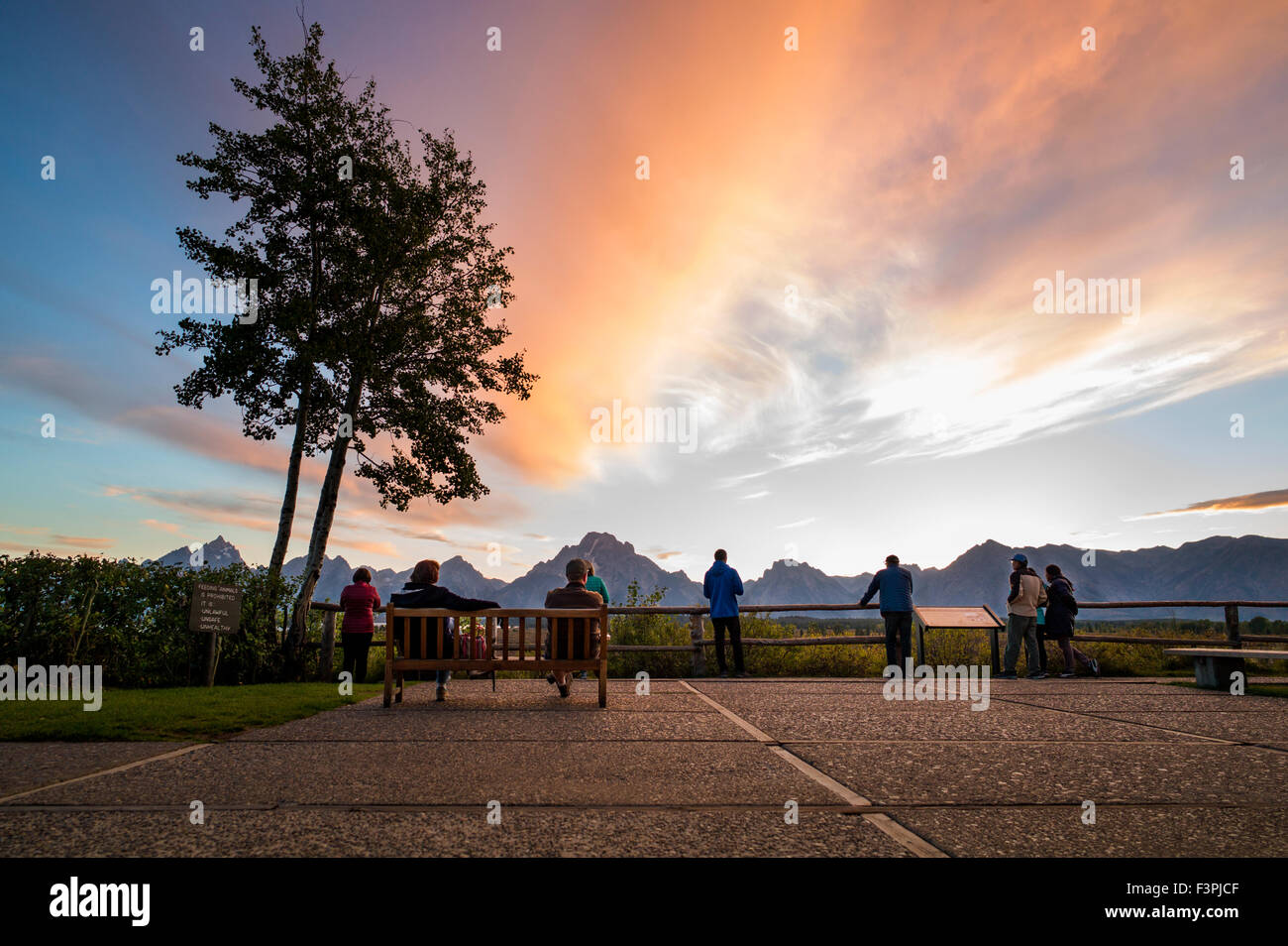 Touristen genießen Sie Blick auf den Sonnenuntergang von der Terrasse des berühmten & historischen Jackson Lake Lodge; Grand Teton Nationalpark; Teton Range Stockfoto