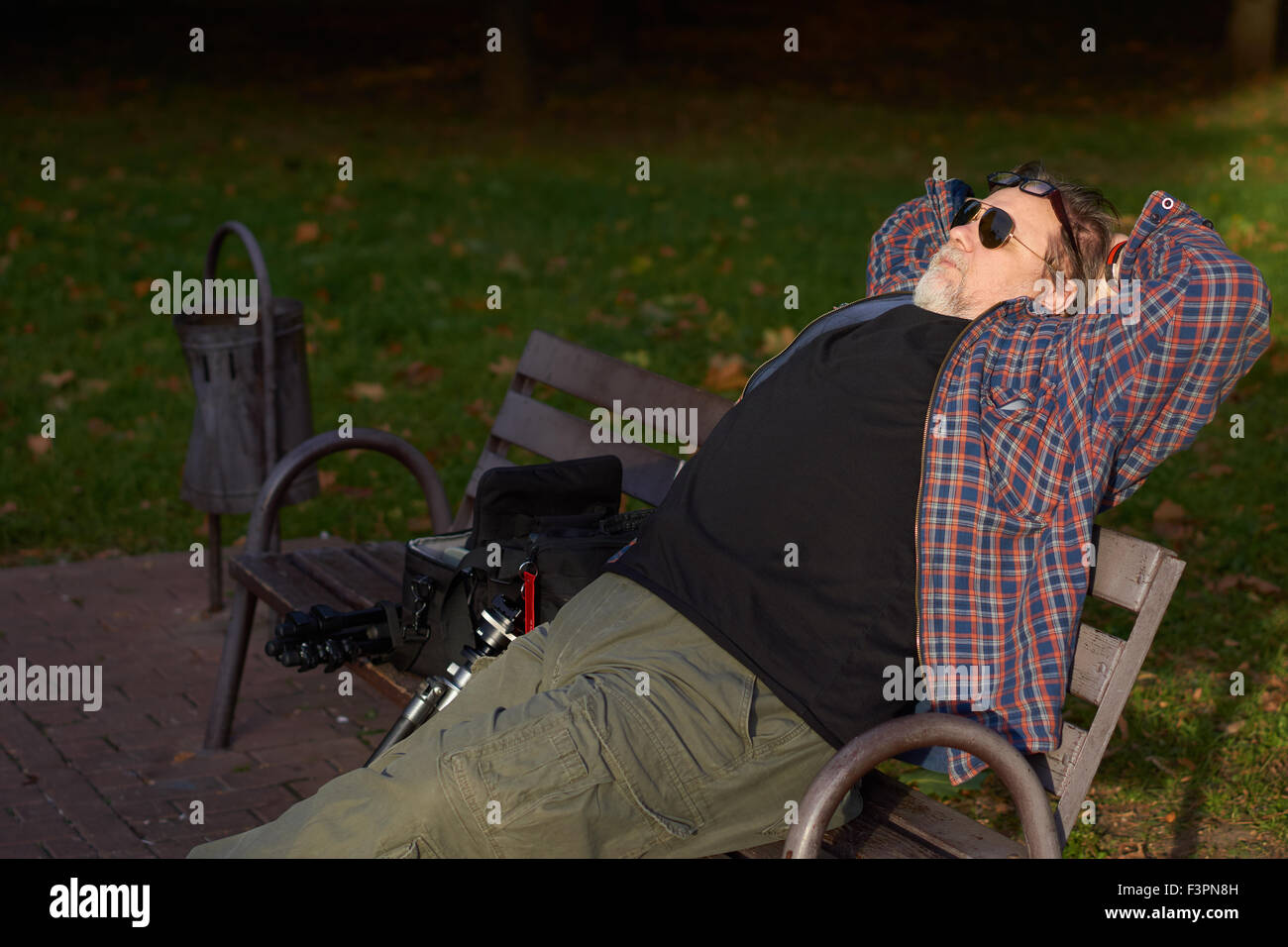 Mann mittleren Alter mit Bart in Sonnenbrille hat Rest auf der Bank im Herbst park Stockfoto