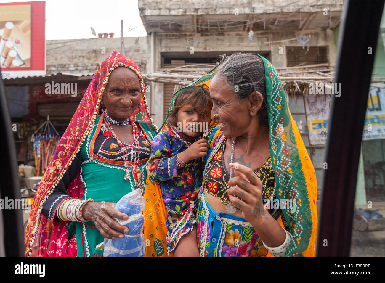Rajasthani Frauen in traditionellen Kostümen zeigt ein Kind, ein Tourist in ein Taxi. Stockfoto