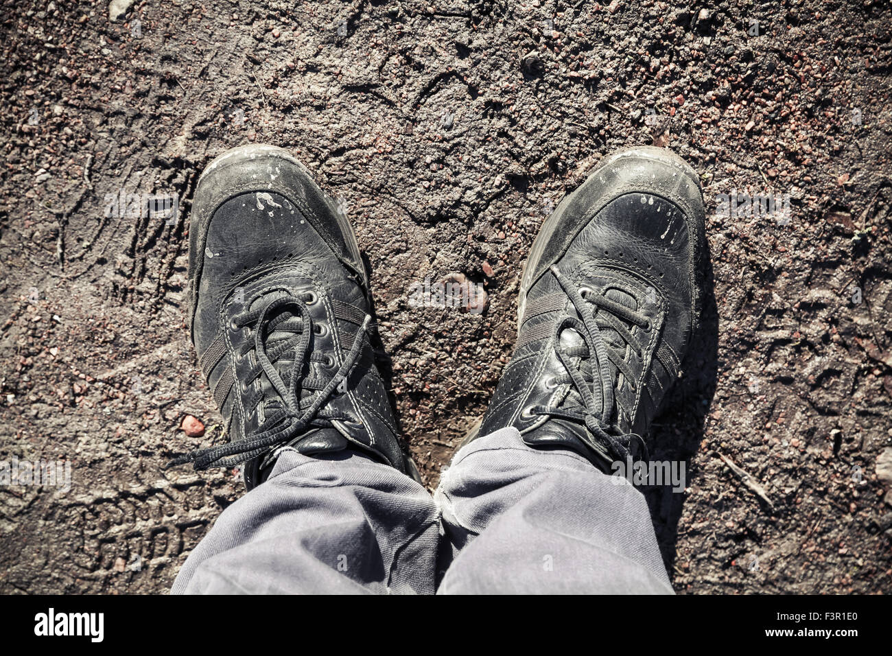 Männliche Füße in schmutzigen Schuhen auf Straße Schlamm stehend Stockfoto