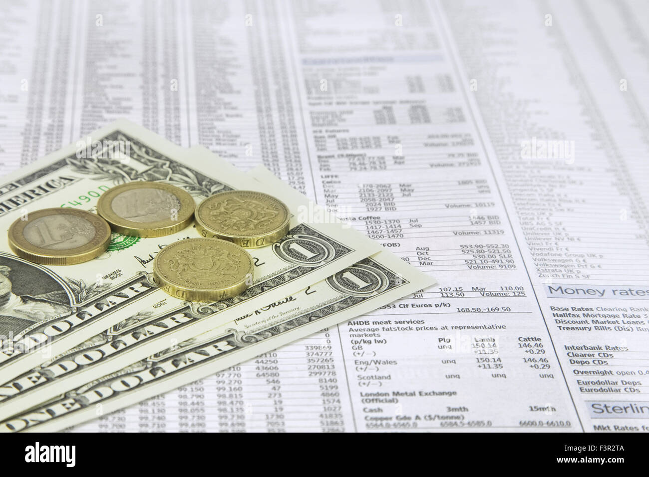 Ein Dollar-Note, ein britisches Pfund und ein Euro-Münzen auf einer News Papier Börse finanzielle Seite zeigen, Aktien und Anteile Stockfoto