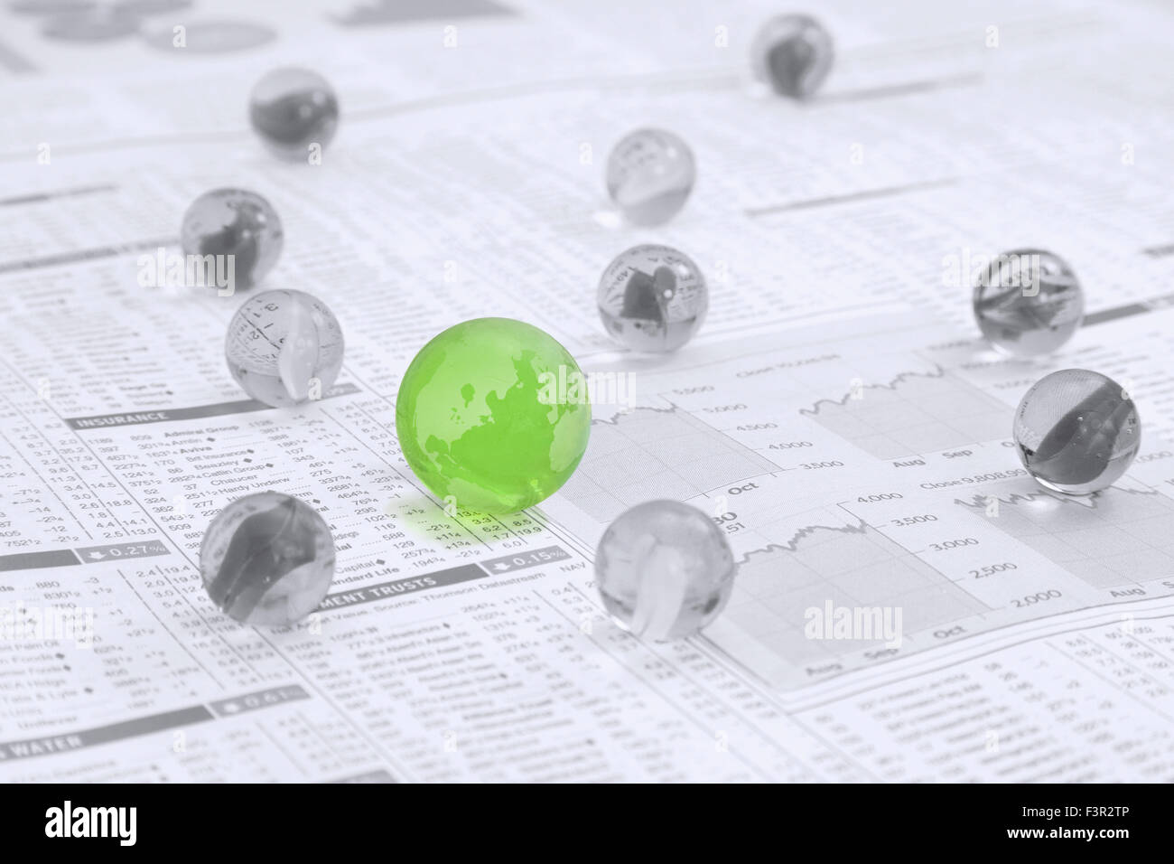 Schwarz / Weiß-Marmor mit einem großen grünen Marmor wie die Karte von der ganzen Welt auf einer Nachrichtenseite Papier zeigen, Aktien und Anteile Stockfoto