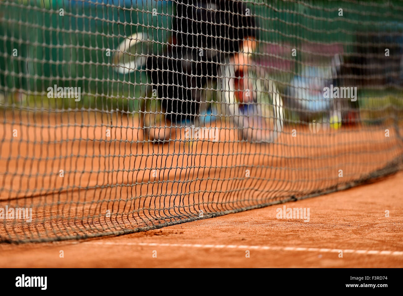 Unkonzentriert Rollstuhl-Tennis-Spieler ist hinter einer Tennis net auf einem Sandplatz gesehen. Stockfoto