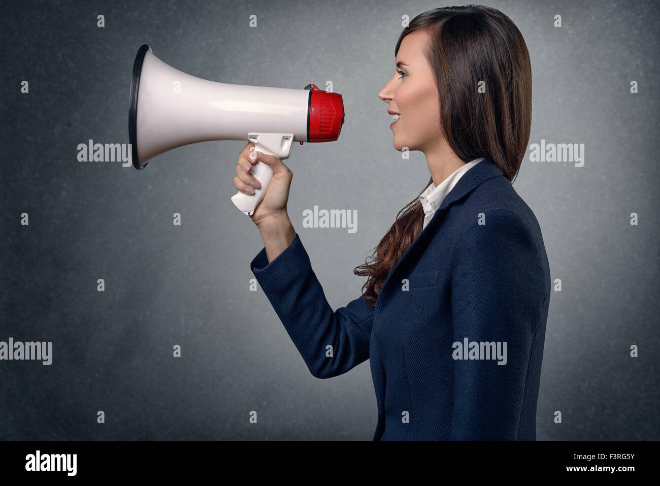 Richtungskontrolle Blick der jungen Frau im langen Ärmeln Seidenhemd, schreien mit Megaphon vor einem abstrakten Hintergrund. Stockfoto