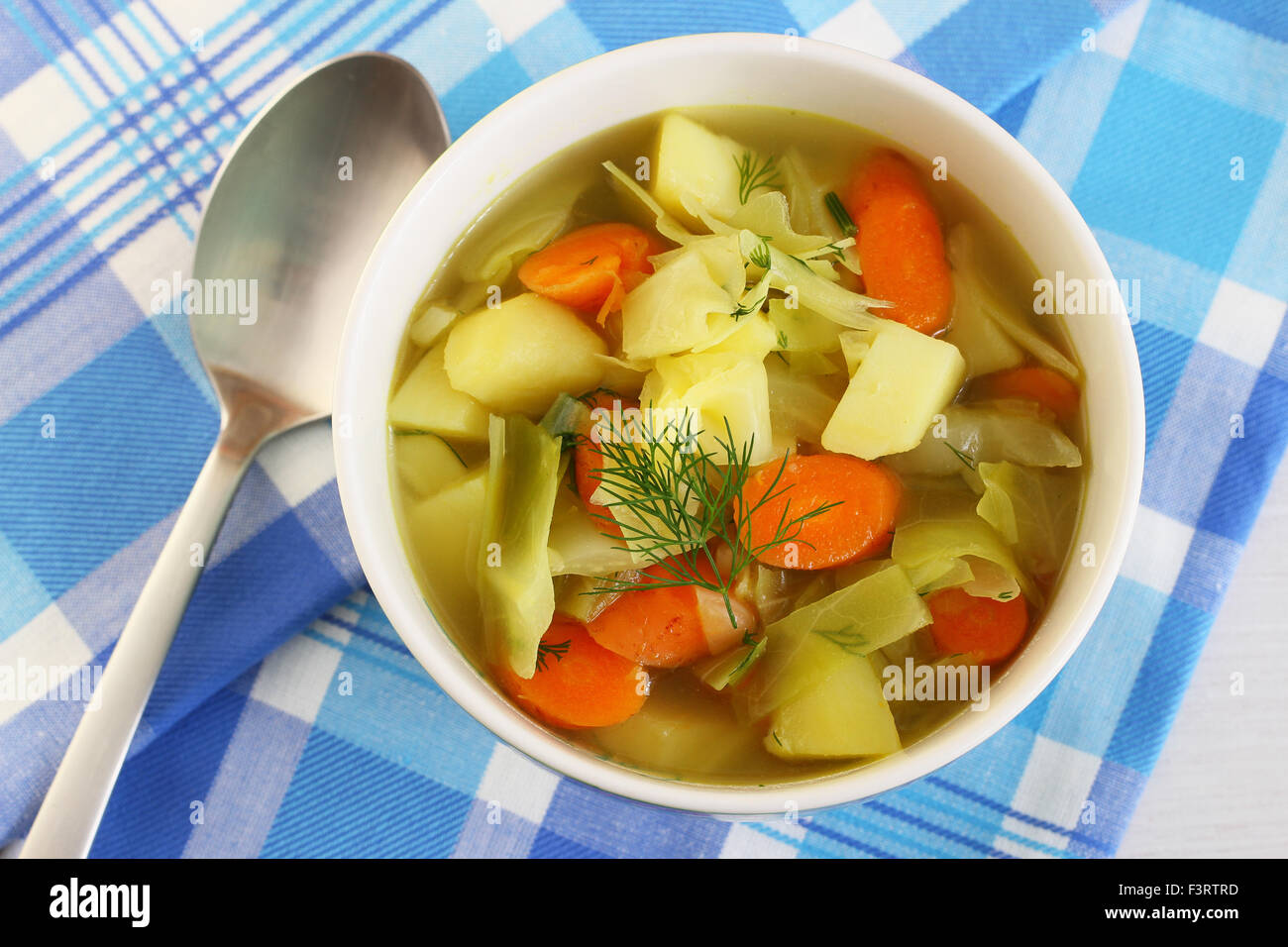 Kohlsuppe in Schüssel, garniert mit frischem Dill auf kariertem Stoff Stockfoto