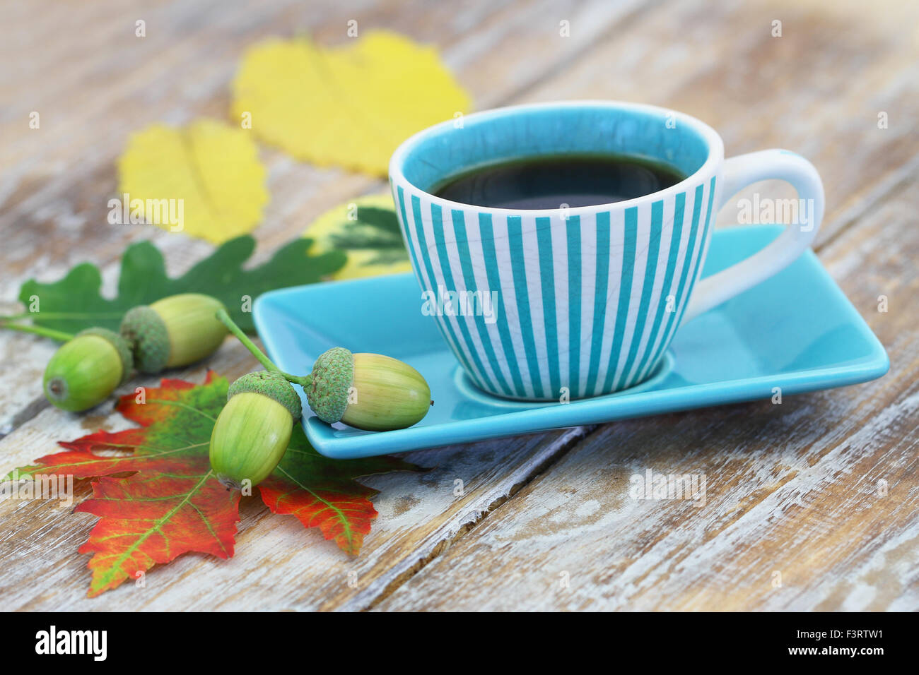 Tasse Kaffee und Herbstliches Laub und Eicheln auf rustikalen Holzoberfläche Stockfoto