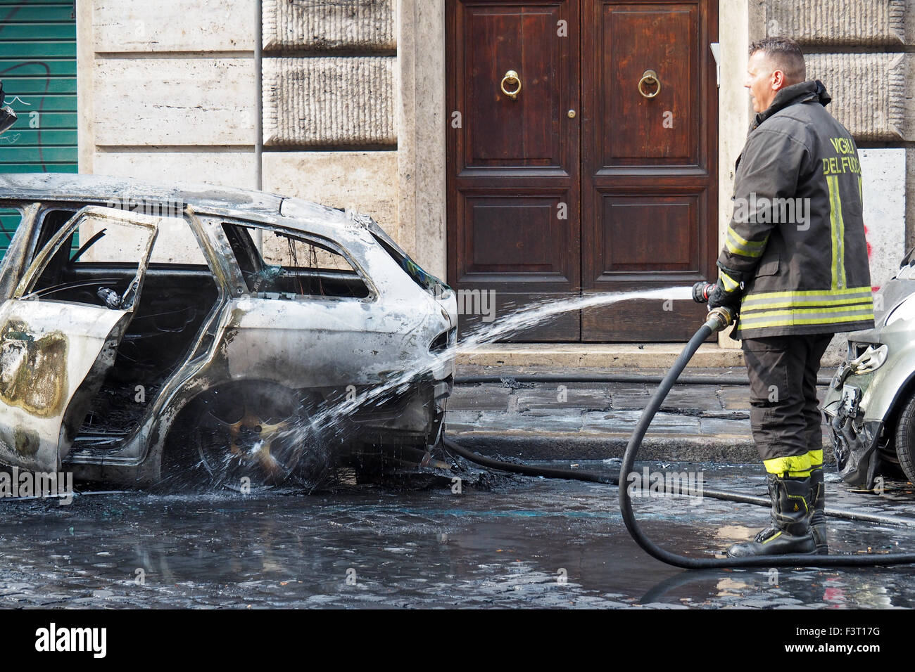 Feuerwehr Schlauch einen verbrannten Fahrzeug. Stockfoto