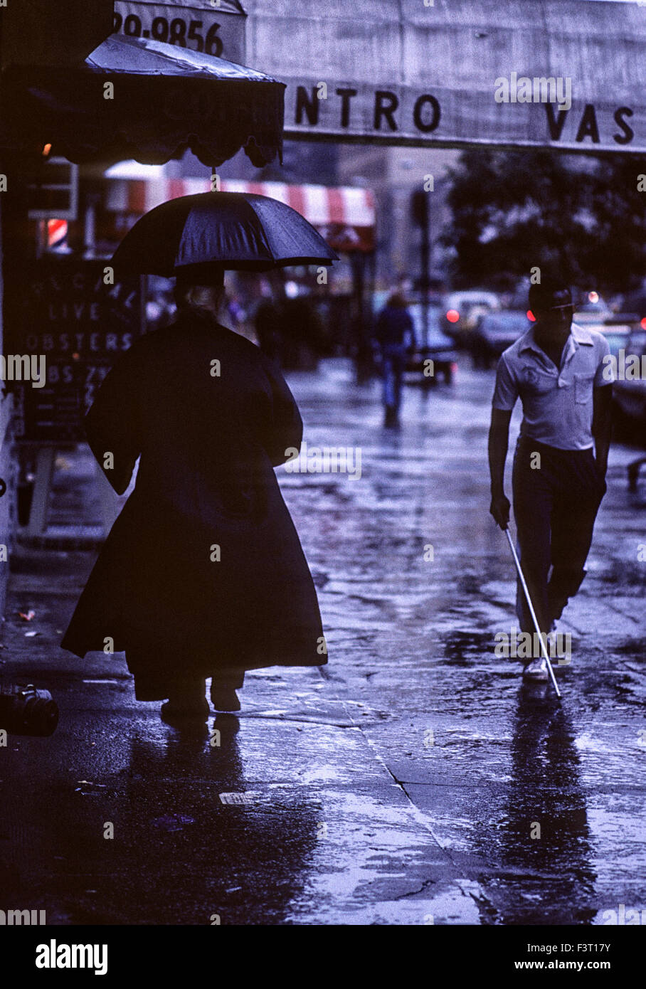 Priester vorbei ein blinder Mann in nassen New Yorker downtown Street, 1981 Stockfoto