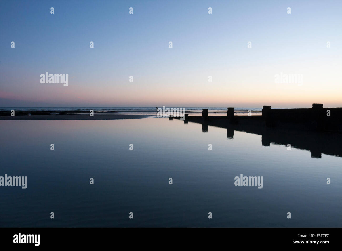 Reflexionen in der Dämmerung und einsame Abbildung auf einem ruhigen Strand, Bexhill-on-Sea, East Sussex, England, Großbritannien Stockfoto