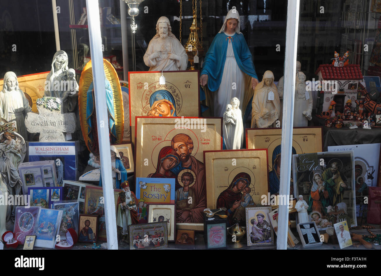 Christliche Utensilien für den Verkauf in einem Schaufenster in kleinen Walsingham, Norfolk, England. Stockfoto