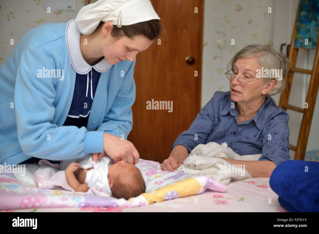 Leitende Hebamme prüft ein neugeborenes Baby mit ihrer Mutter Stockfoto