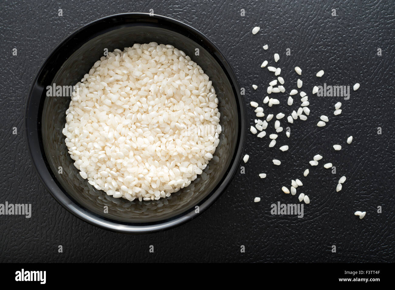 Schwarze Schale voll Reis auf dunklem Hintergrund Stockfoto