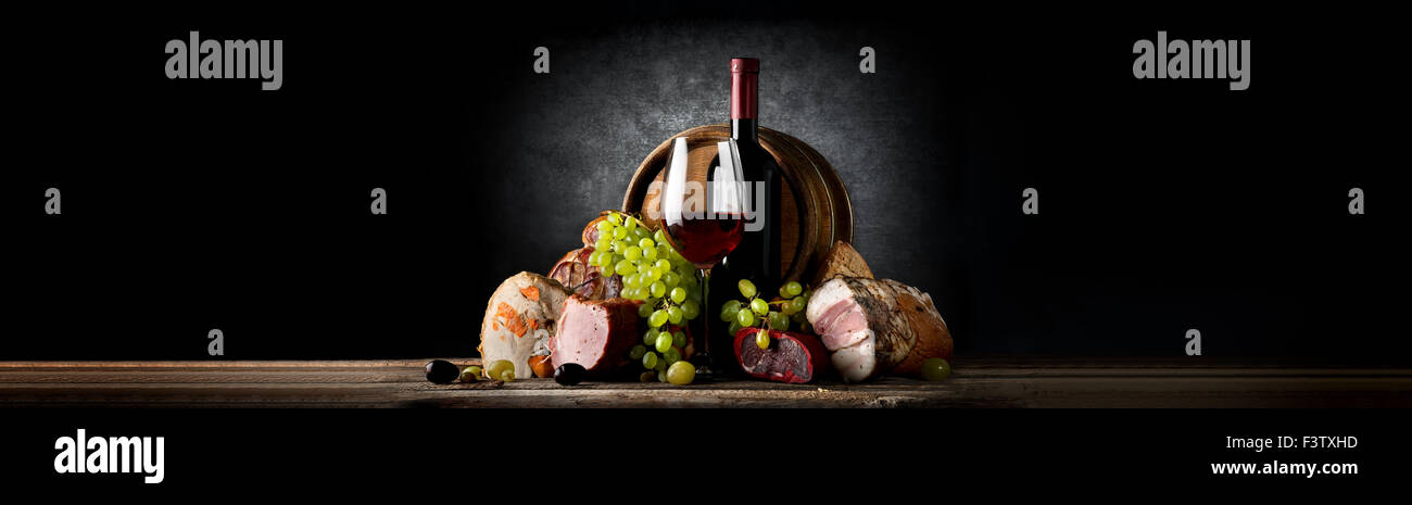 Komposition mit Wein und Essen auf einem schwarzen Hintergrund Stockfoto
