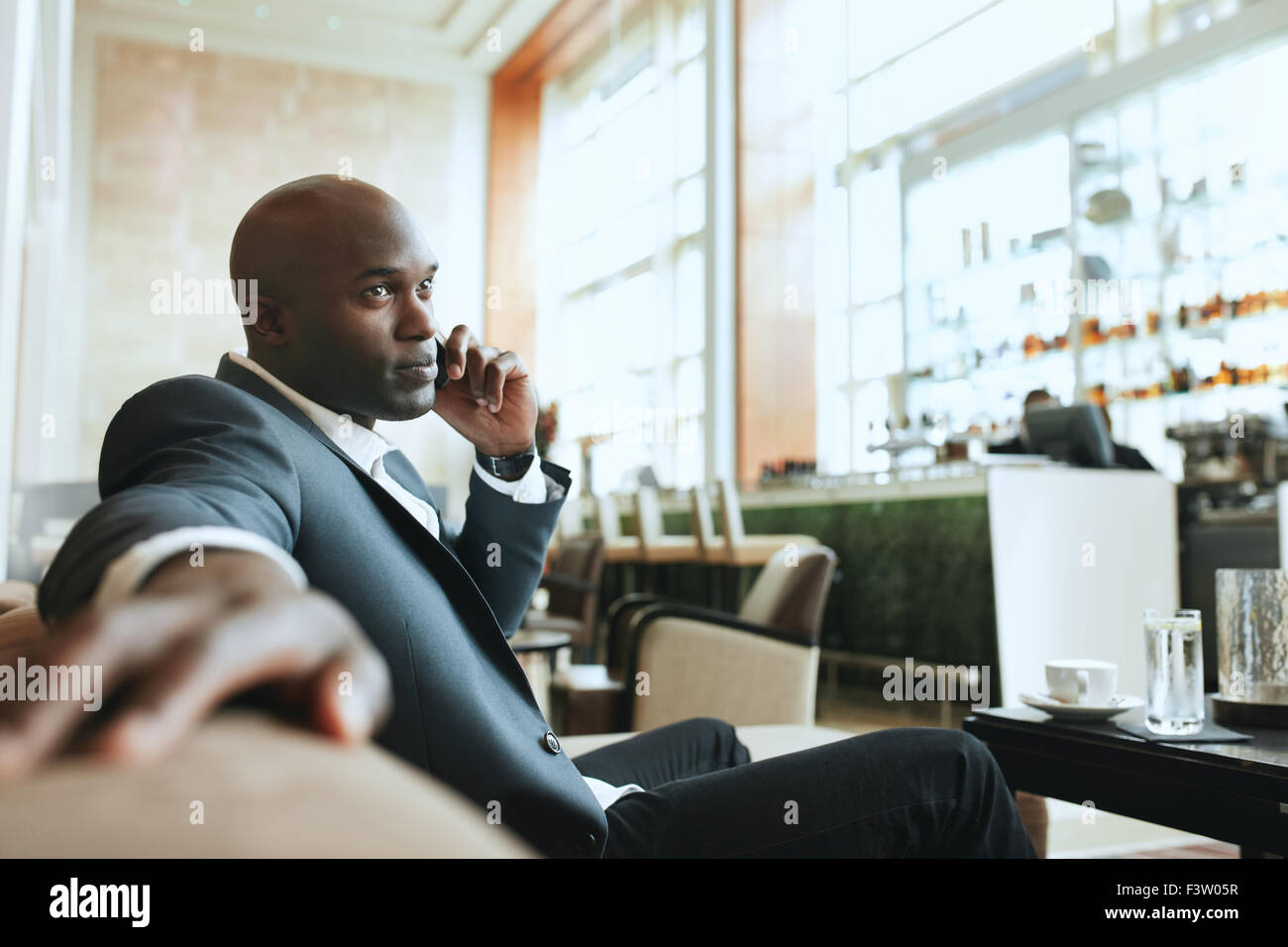 Afrikanischen Geschäftsmann telefonieren mit Handy während der Wartezeit in einer Hotel-Lobby. Junger Geschäftsmann mit Handy während der wai Stockfoto