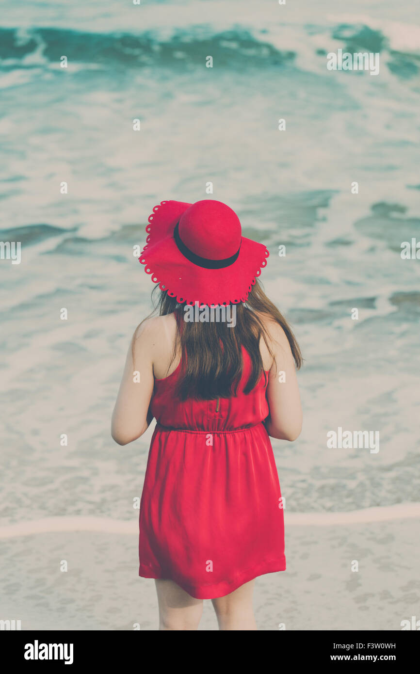 Junge Frau in einem roten Kleid am Strand Stockfoto