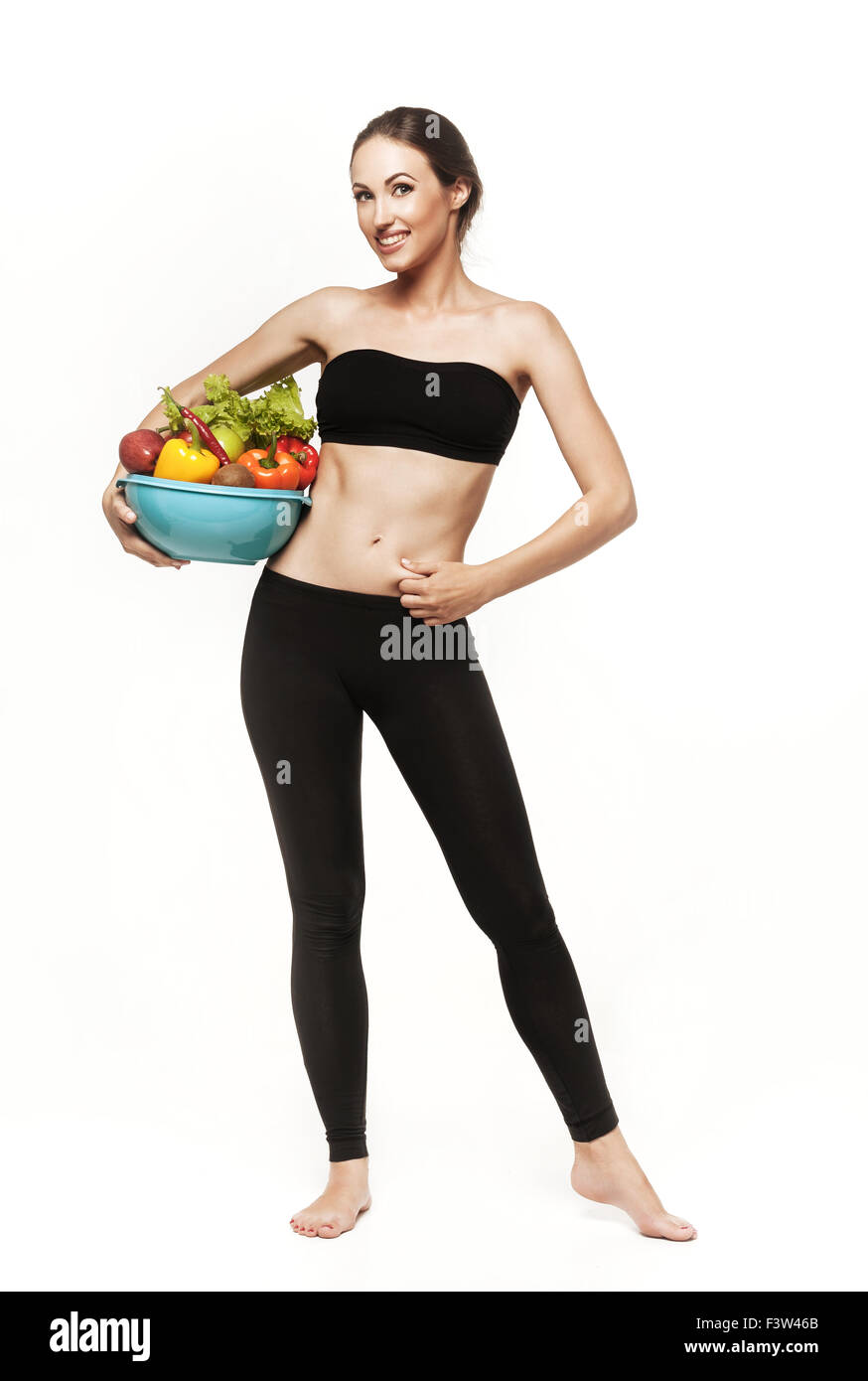 Schöne junge Brünette Frau mit schlanken Körper hält Schüssel mit Obst und Gemüse. Gesunde Ernährung, Lebensstil und Gewichtsverlust Stockfoto
