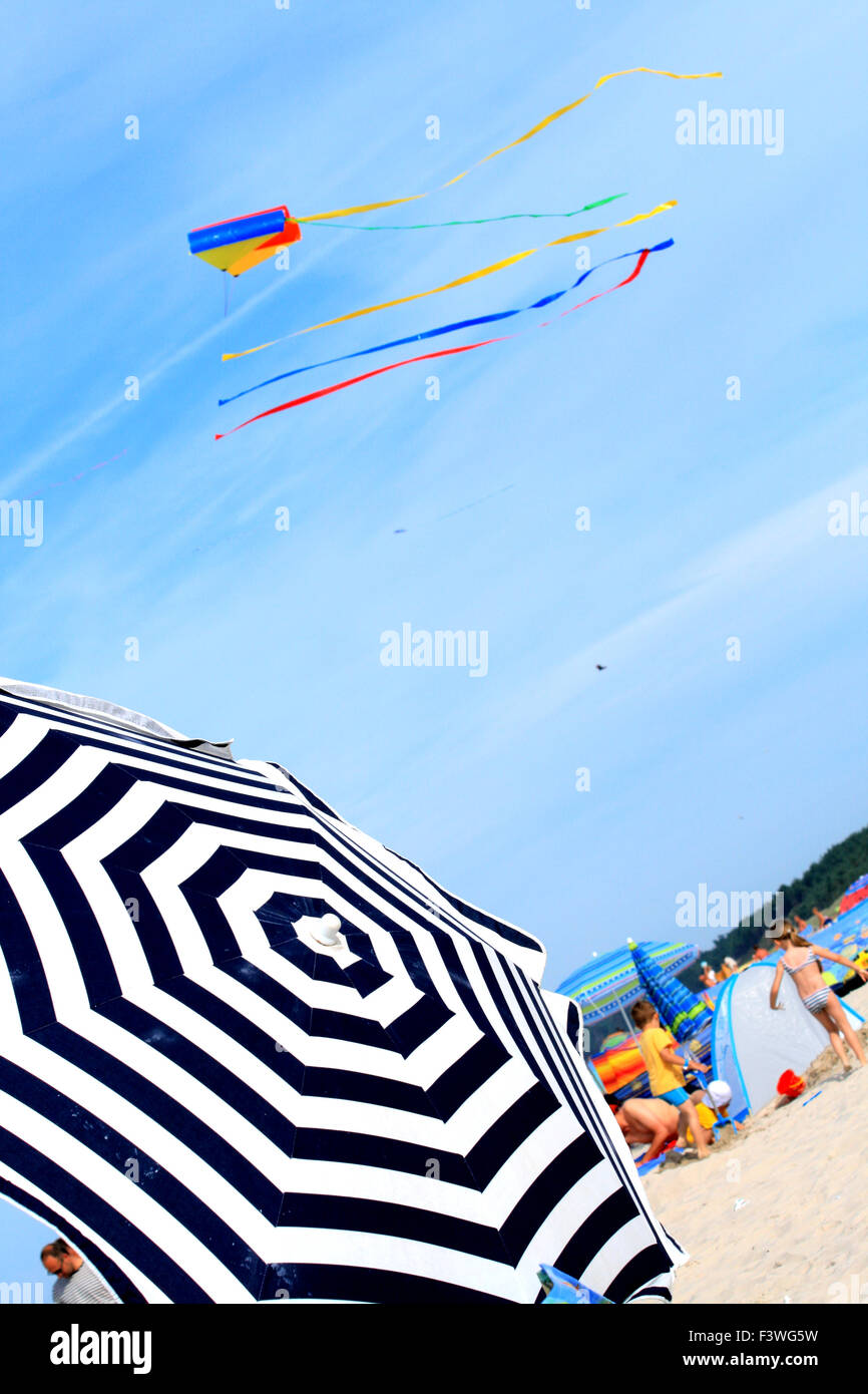 Sonnenschirm und Drachen am Strand Stockfoto