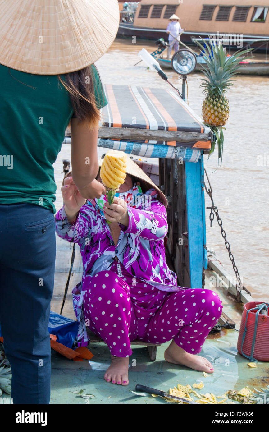 junge vietnamesische Frau Dame kauft eine Ananas von einem Lieferanten in Cai Rang schwimmende Märkte, Can Tho, Mekong-Delta, Vietnam Stockfoto