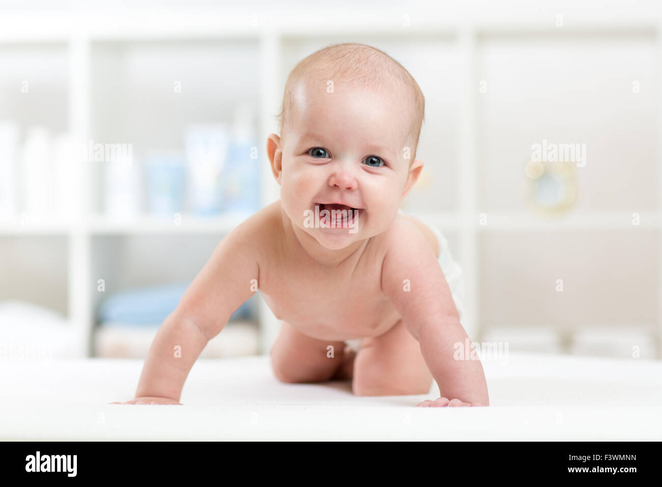glückliches Baby Kind krabbeln auf Bett und lächelnd Stockfoto