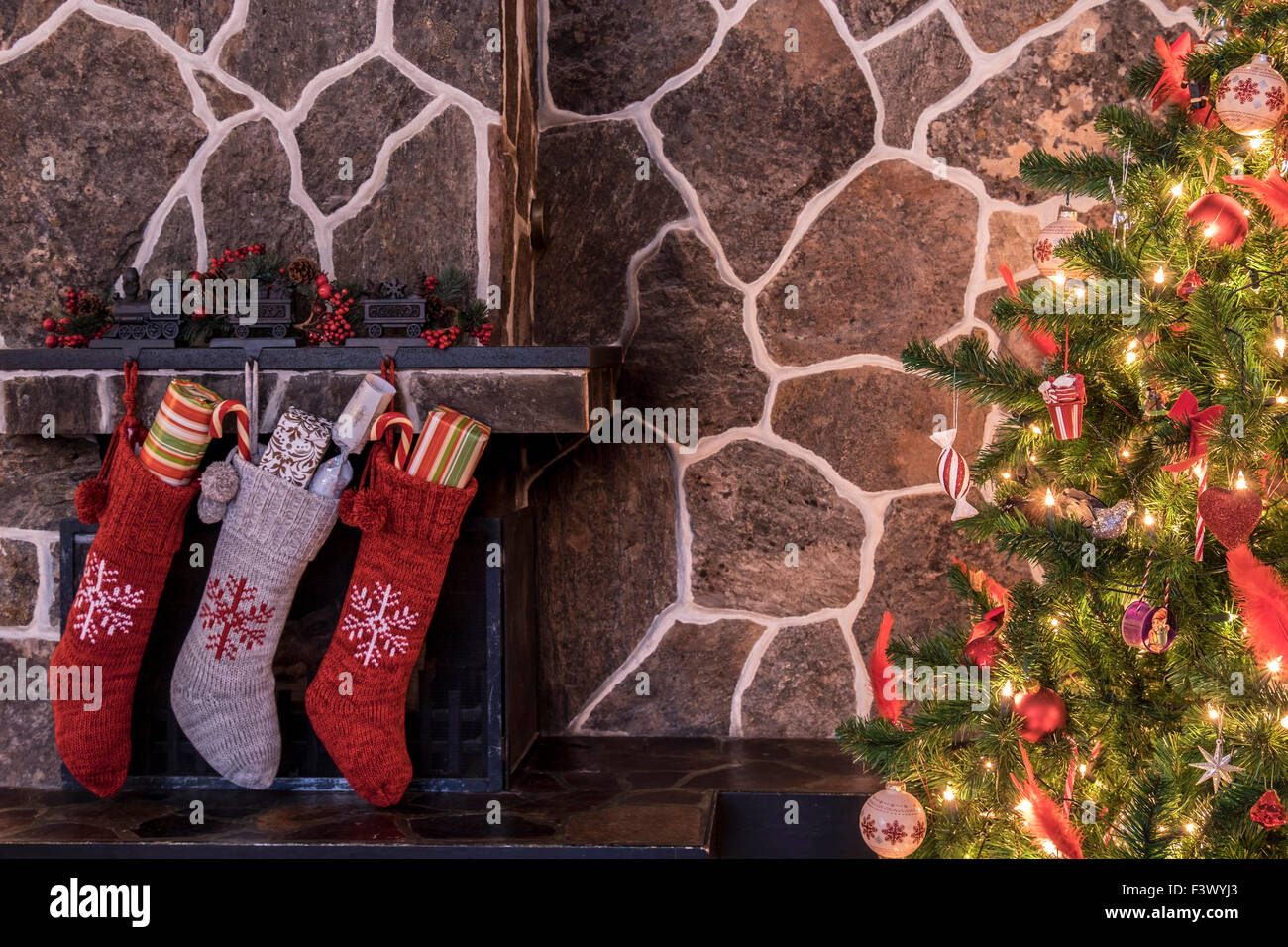 Strümpfe, die an einen Kamin neben einem Weihnachtsbaum hängen am Weihnachtsmorgen Stockfoto