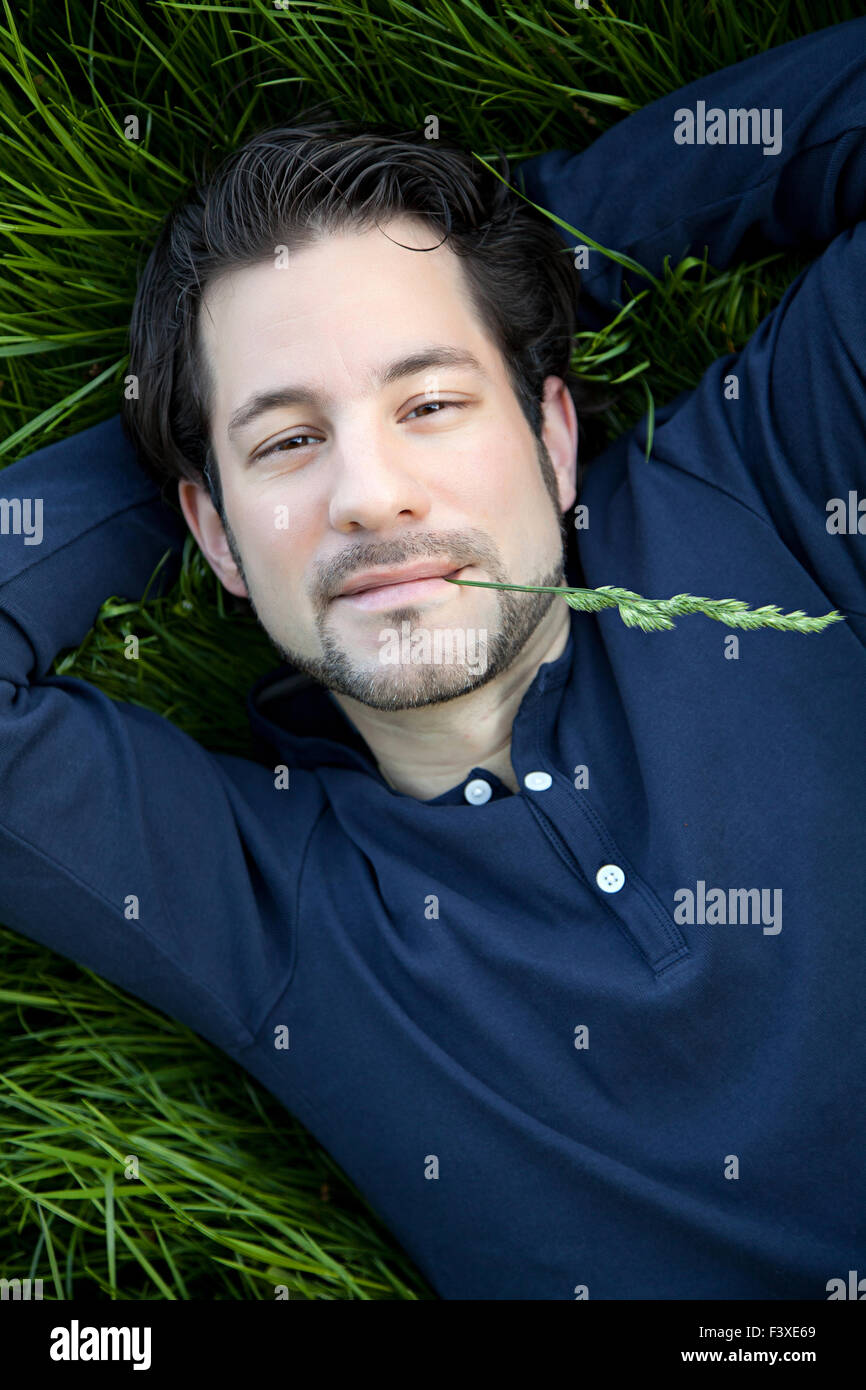 schöner junger Mann auf grünem Gras liegend Stockfoto