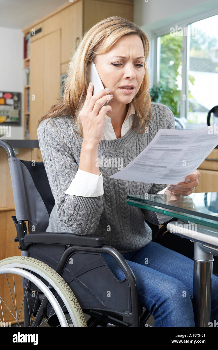 Frustrierte Frau im Rollstuhl Anruf tätigen, während Brief lesen Stockfoto