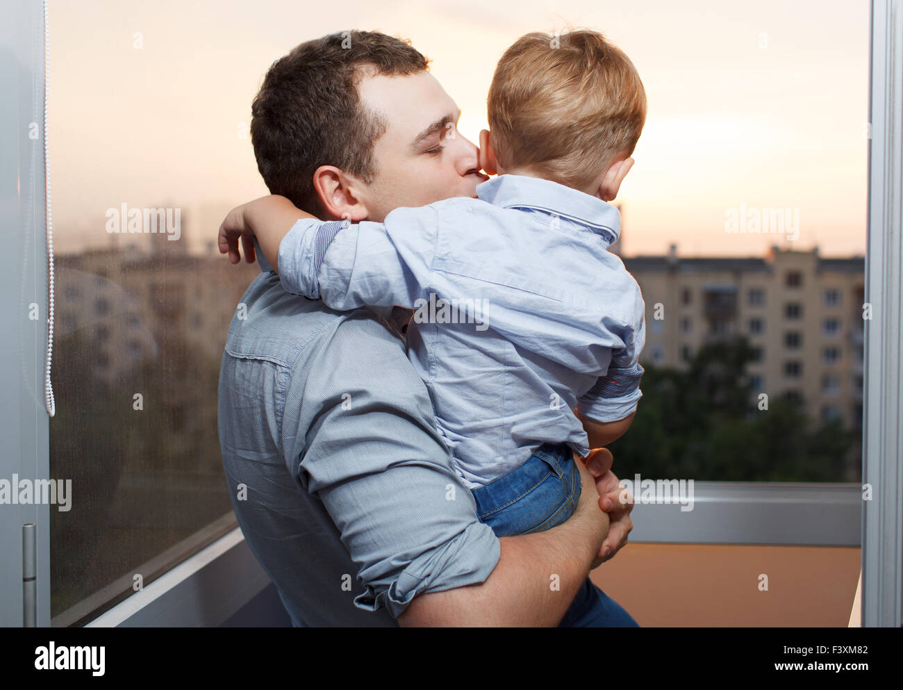 Vater küsst seinen Sohn auf dem Balkon Stockfoto