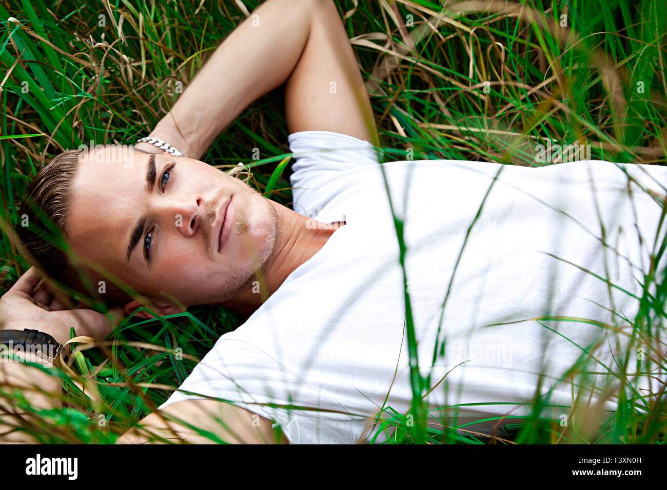 schöner junger Mann auf grünem Gras liegend Stockfoto