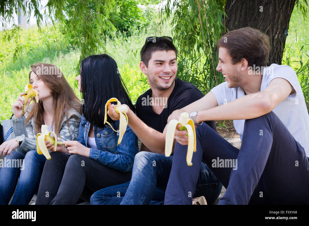 Reihe von Freunden zusammensitzen Banane essen Stockfoto