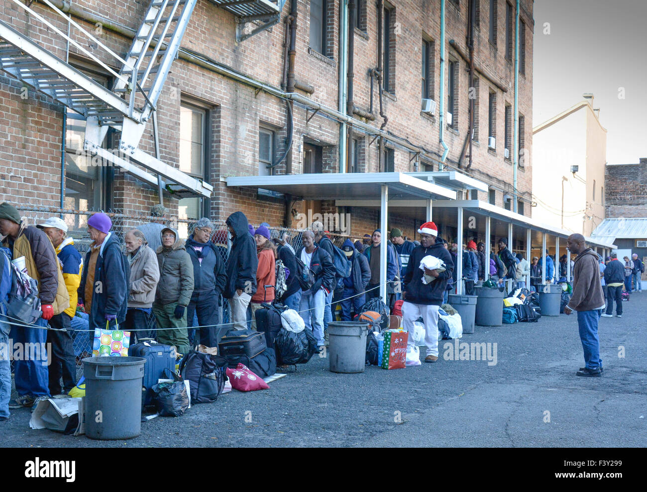 Menschen aller Rassen und Altersgruppen stehen in der Schlange warten ihrerseits für Lebensmittel und Kleidung Spenden bei Charity-mission Stockfoto