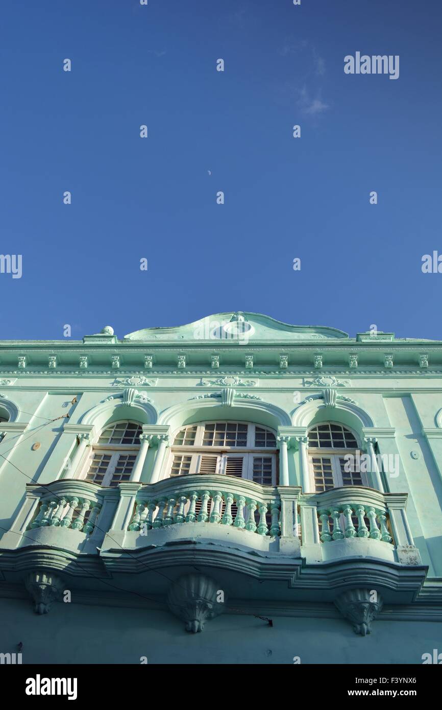 Pastell Grün Fassade des alten Kolonialgebäude, Santa Clara, Kuba mit Balustrade Balkon unterhalb der Fenster und blauer Himmel Stockfoto