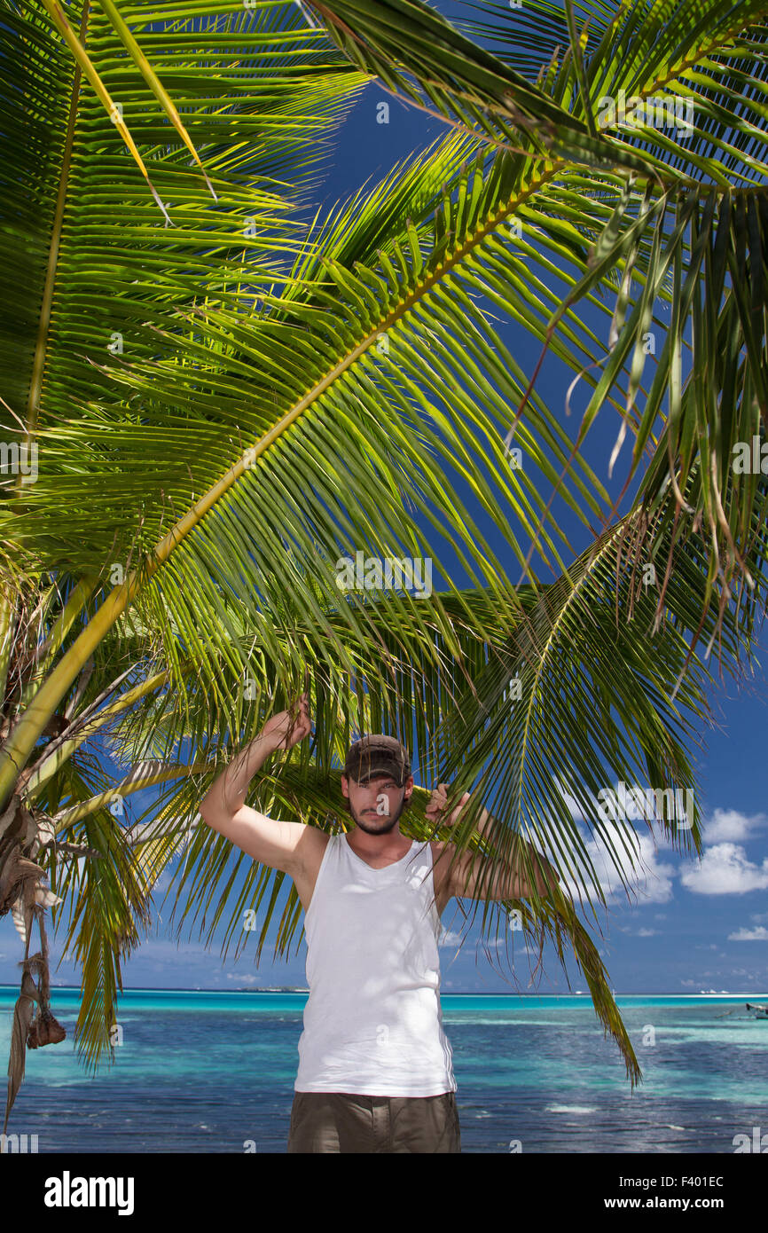 Mann steht unter Palm Tree am tropischen Strand Stockfoto