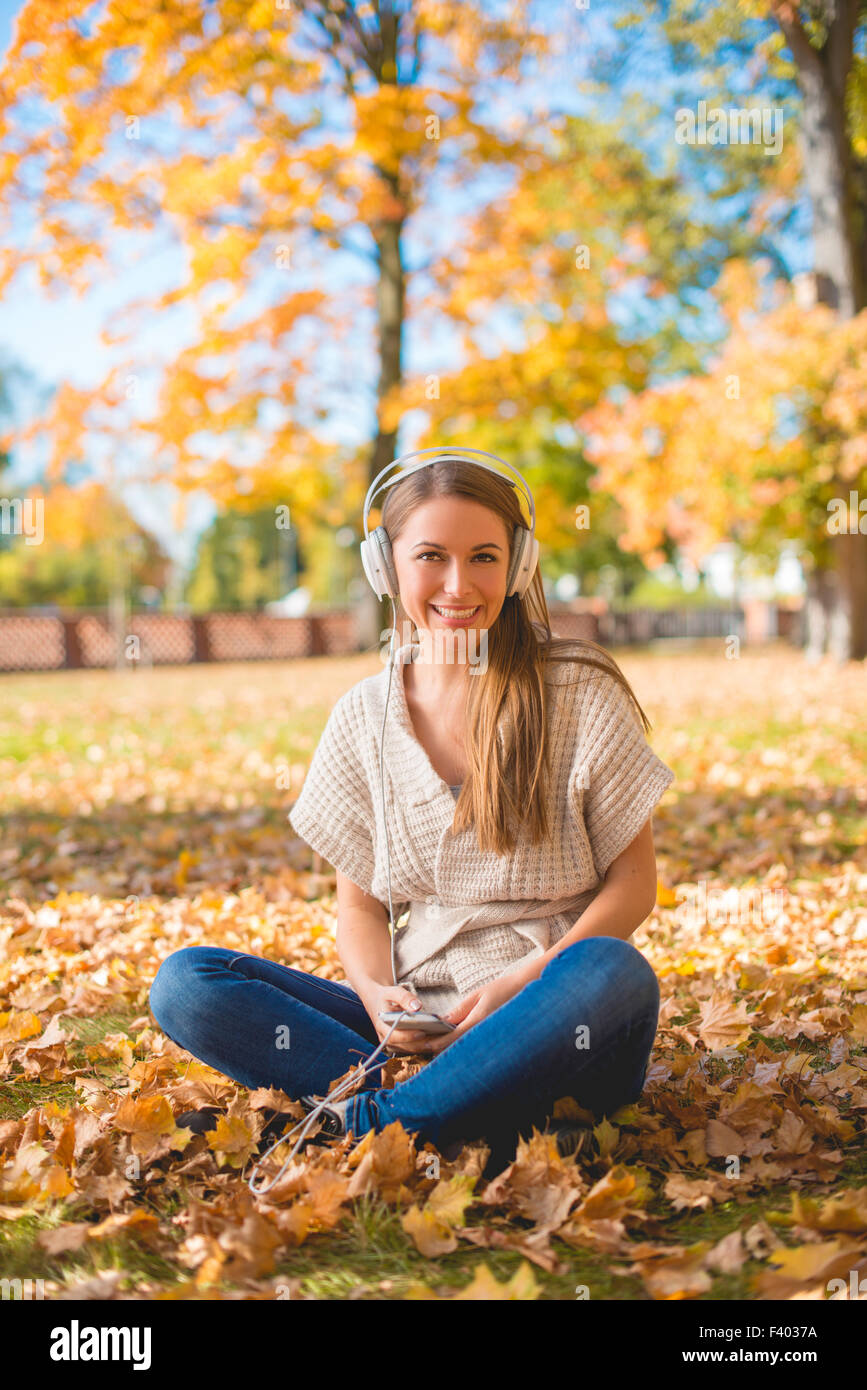 Lächelnde Frau anhören von Musik in einem Herbst-park Stockfoto