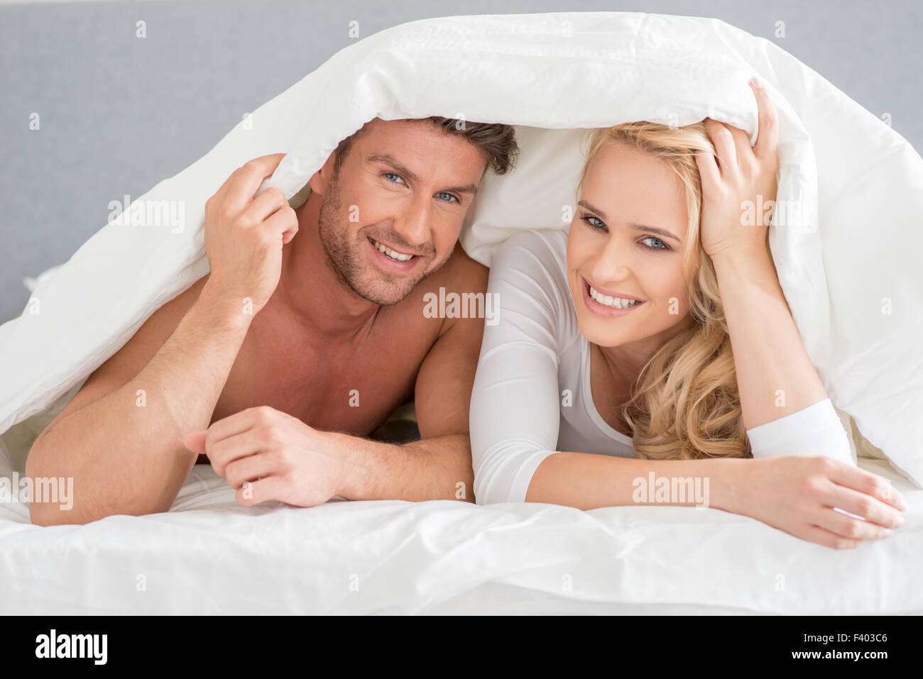 Junges Paar, die sich in die Bettdecke abdeckt Stockfoto