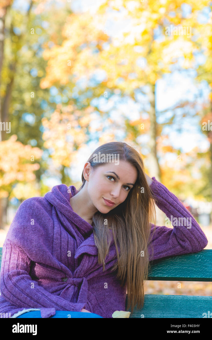 Hübsche Frau im Herbst Outfit auf Bank sitzend Stockfoto