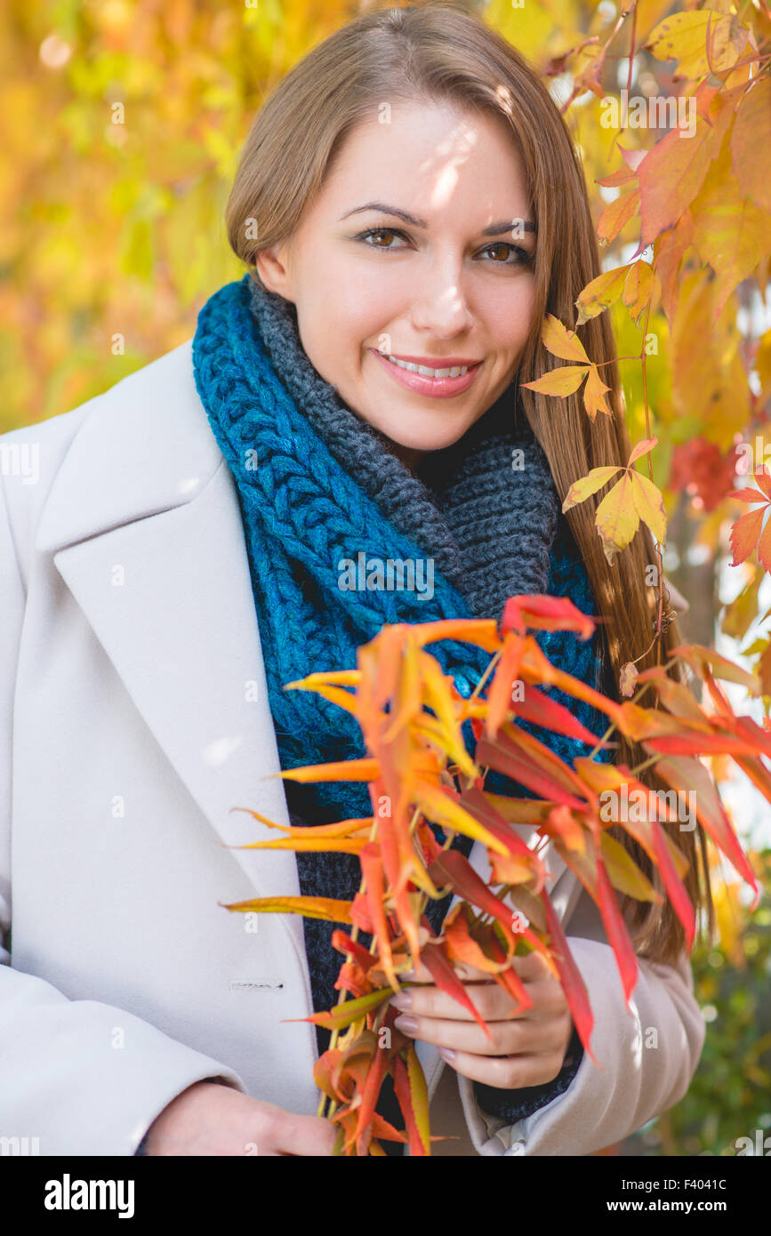 Stilvolle junge Frau Kommissionierung Herbstlaub Stockfoto