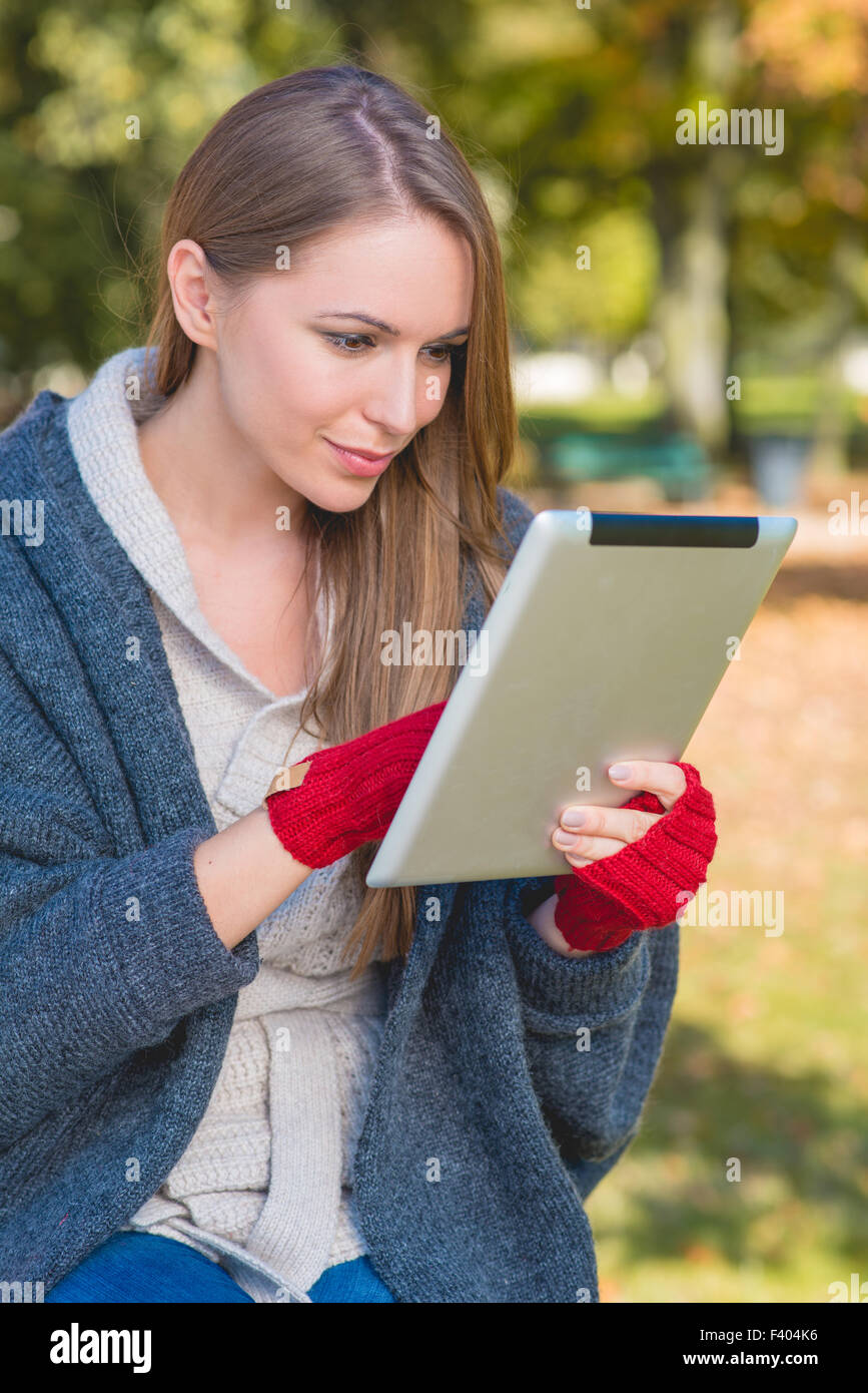 Lächelnde junge Frau beschäftigt mit dem Apple Ipad Stockfoto