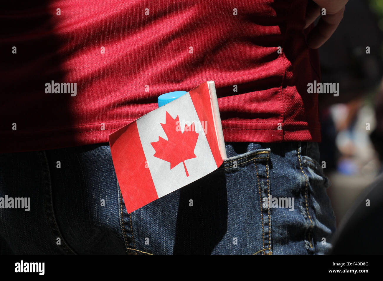 Eine Person trägt ein rotes Hemd und Jeans mit kanadischen Flagge in der Tasche. Stockfoto